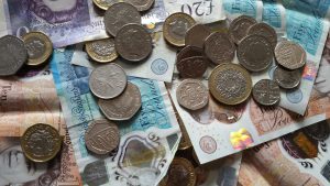 Close-up of various British pound coins and banknotes displaying Queen Elizabeth II's portrait.